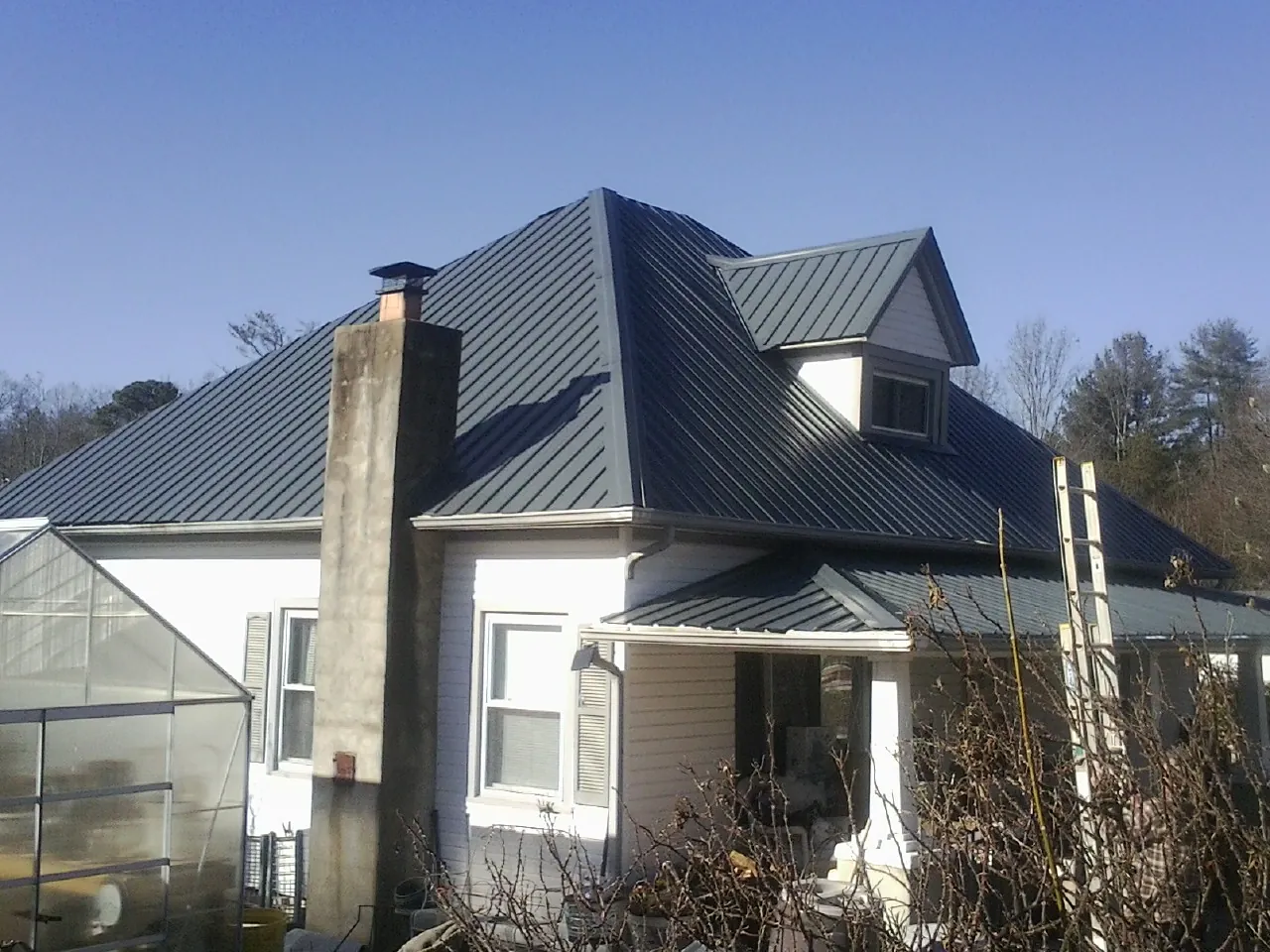 Dark blue standing seam metal roof on a white farmhouse with dormer — Slate & Tile Roof Repair by Roofing Brothers in Hortonville