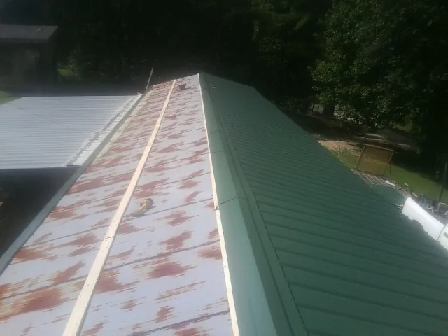 Old rusted panels beside newly installed green metal roofing — Wind Damage Roof Repair by Roofing Brothers in Hortonville