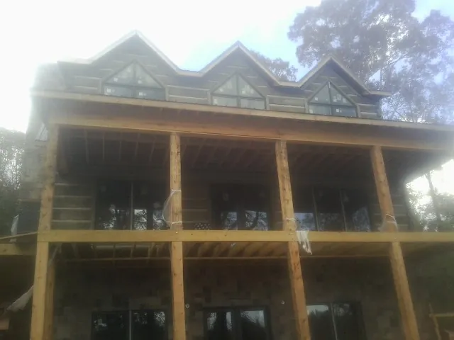 Dormers and porch framing on a large log home under construction — Roof Coating work by our crew in Hortonville