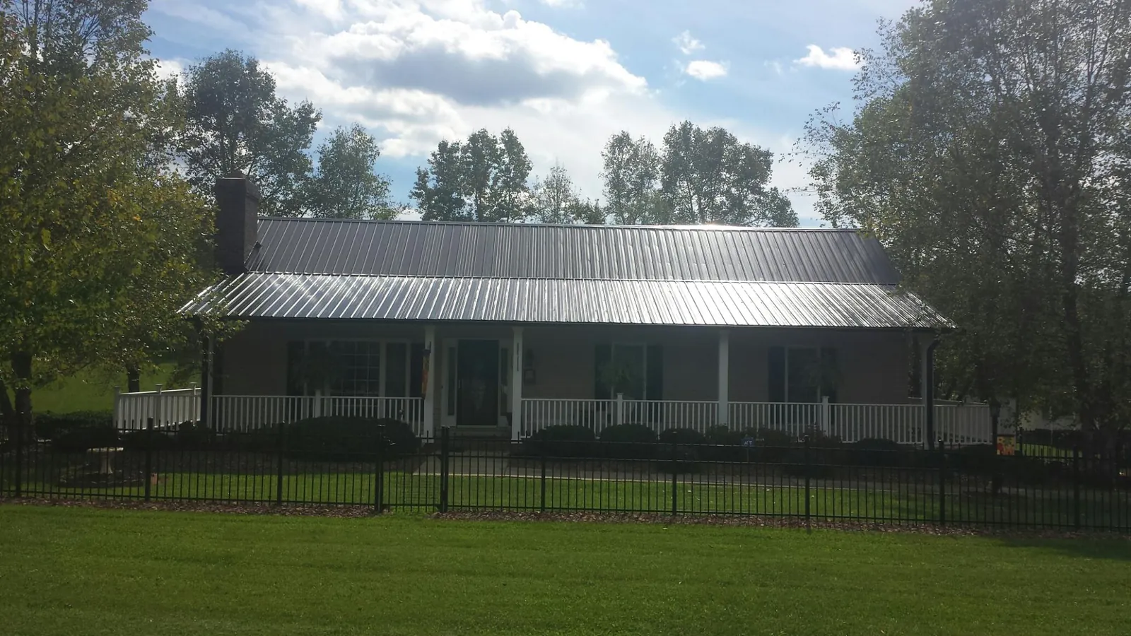 Gray metal roof on a brick ranch with a full width front porch — Gutter Guard Installation work by our crew in Hortonville