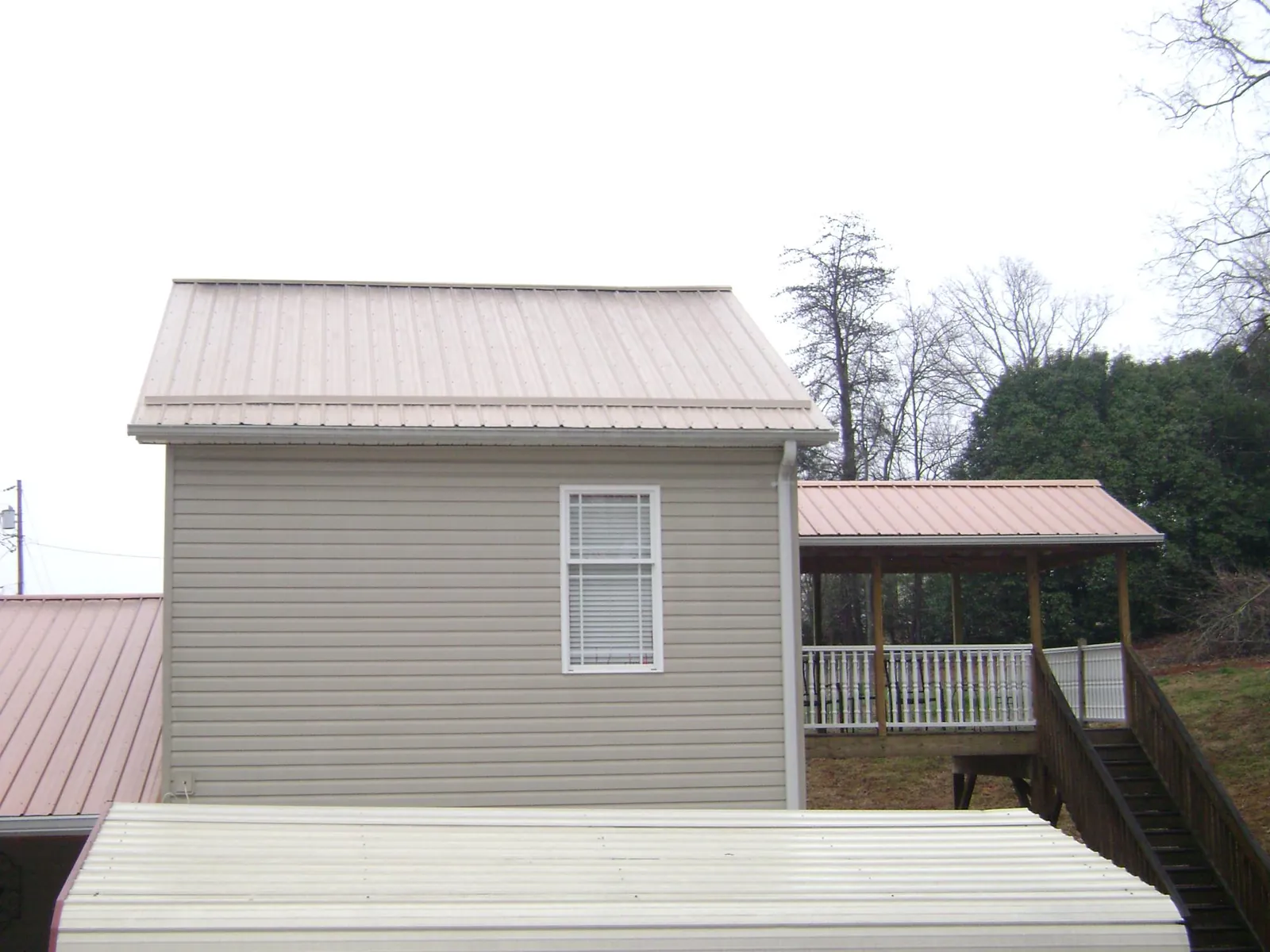Tan metal roofs on a two story addition and attached porch, from a Roof Replacement job in Hortonville