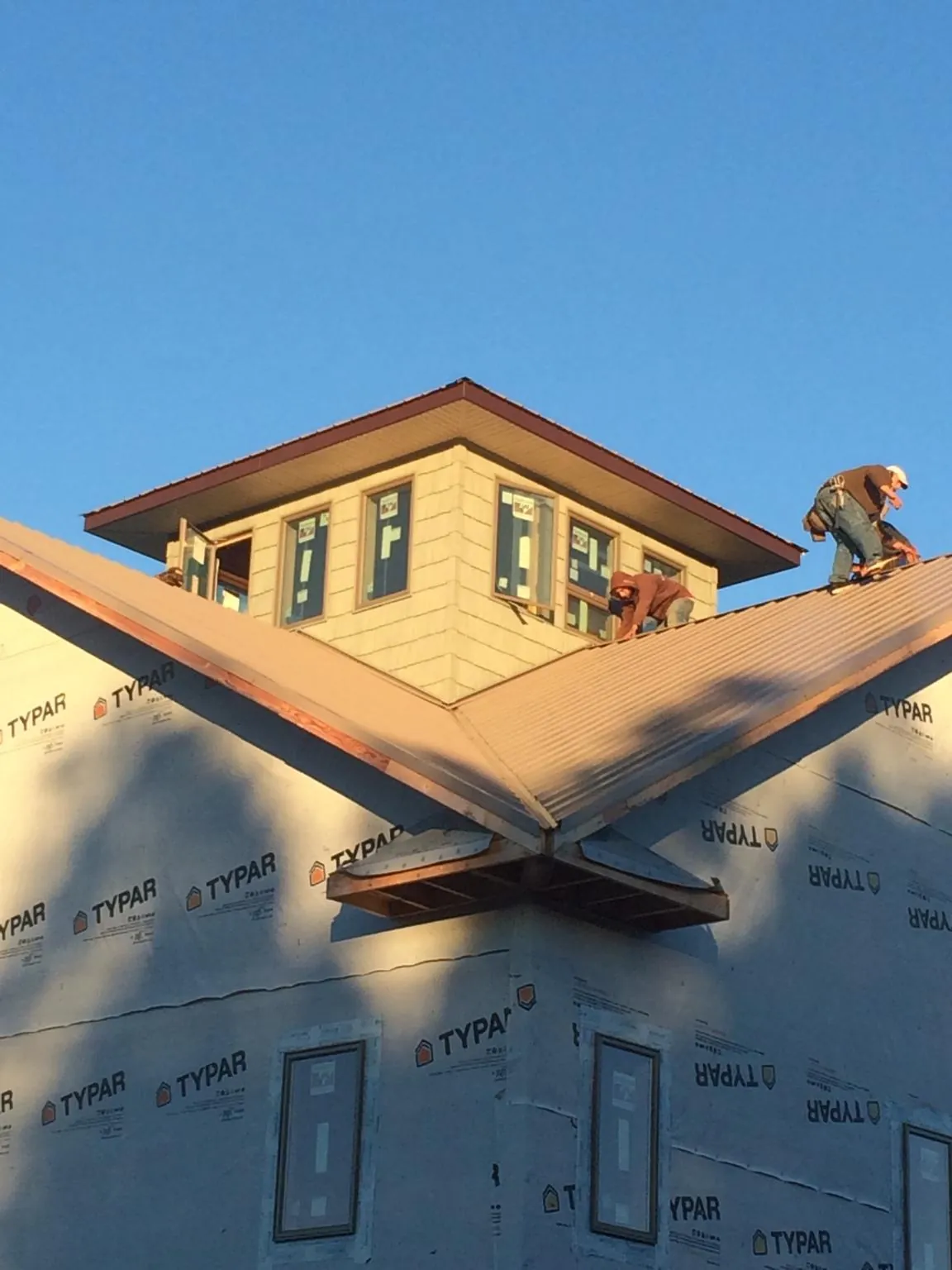 Roofers working around a rooftop cupola on a new metal roof at sunset — Roof Waterproofing in Hortonville by Roofing Brothers
